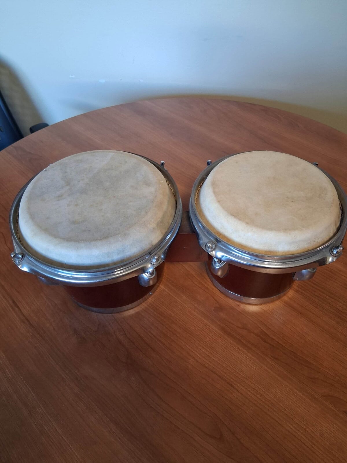 A pair of bongo drums resting on a wooden table.